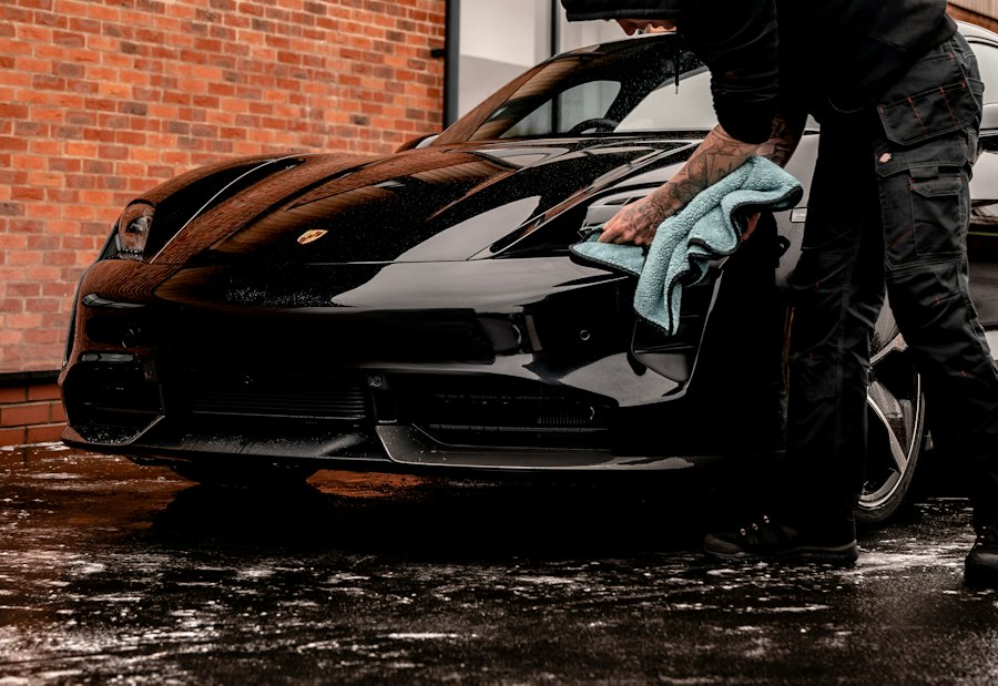 Detailer drying a black Porsche with a microfiber towel