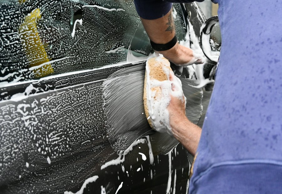 Hand washing a car door with a foam sponge